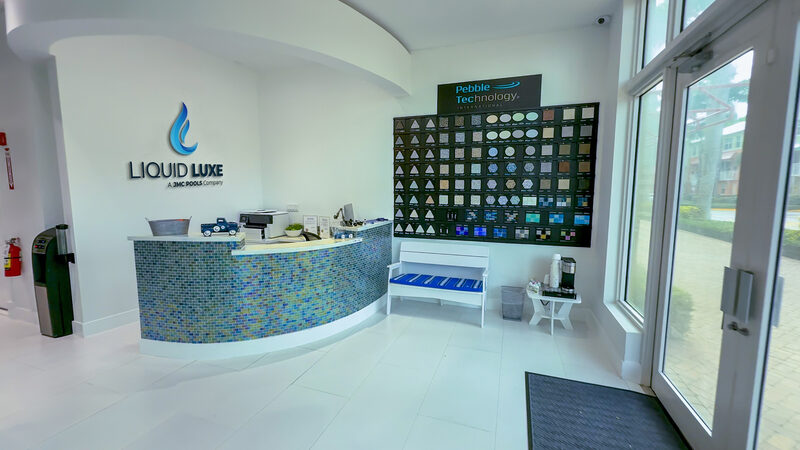 Liquid Luxe showroom reception desk with a wall of pool tile and finish samples