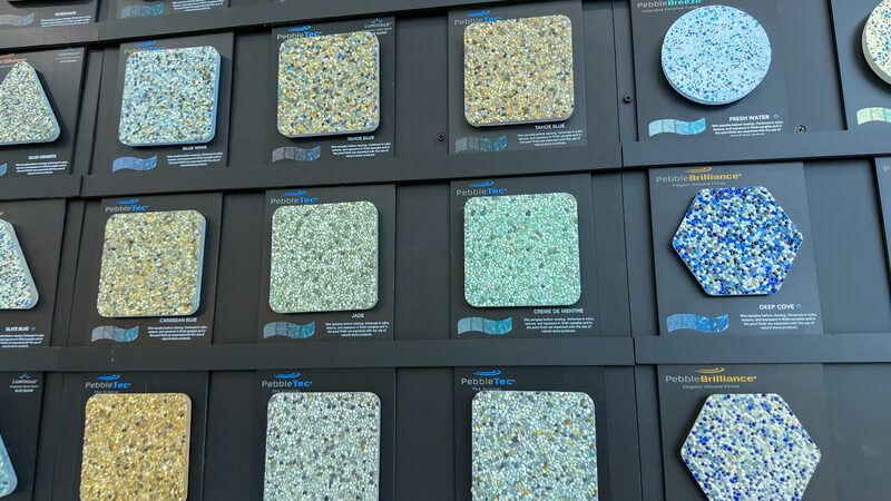 Wall of PebbleTec and PebbleBrilliance pool finish samples